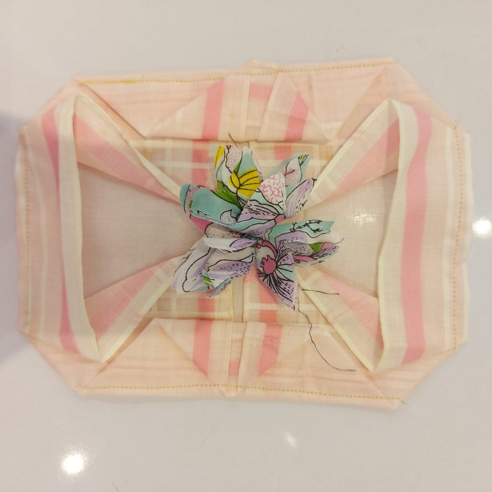 Pink striped fabric folded into an envelope pouch with flower
