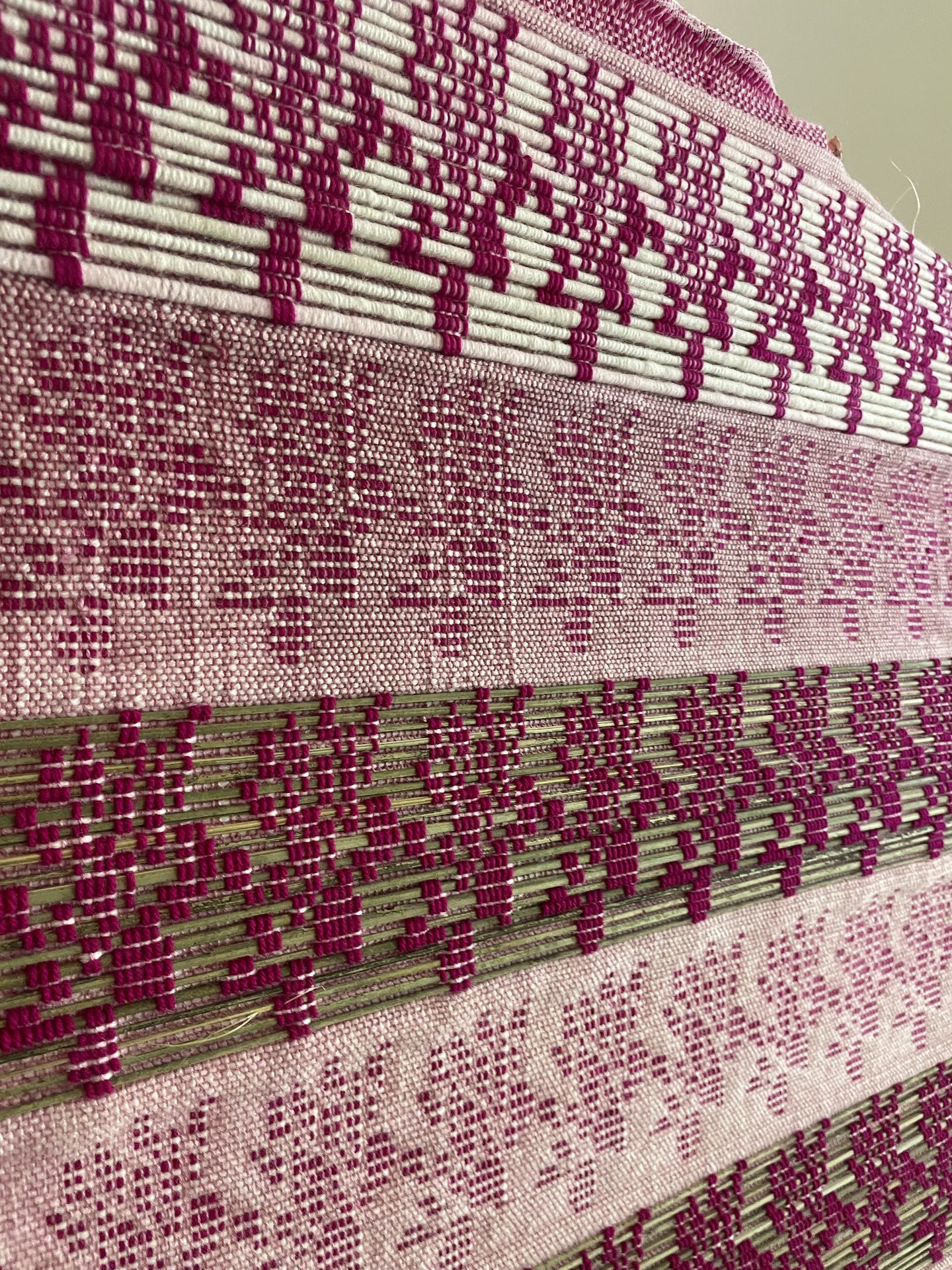 Pink and maroon woven home textile on the loom